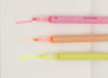 展示粉紅、橘、黃三種顏色的螢光筆在紙上的塗色效果。照片清晰呈現了螢光筆的斜頭（Chisel tip）筆尖設計，以及其鮮豔、半透明的墨水表現。