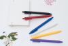 彩色原子筆與白色硬殼筆記本交錯擺放在桌面，呈現產品實際使用情境。